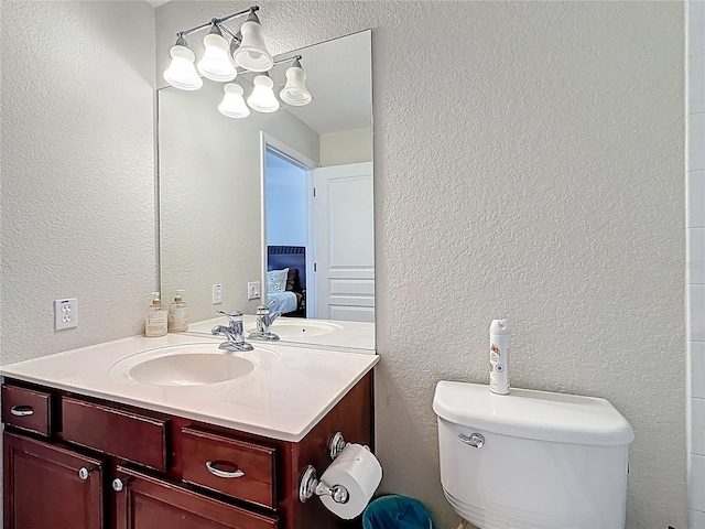 ensuite bathroom with a textured wall, vanity, toilet, and ensuite bathroom