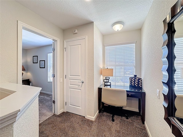 home office with baseboards, dark colored carpet, and a textured ceiling
