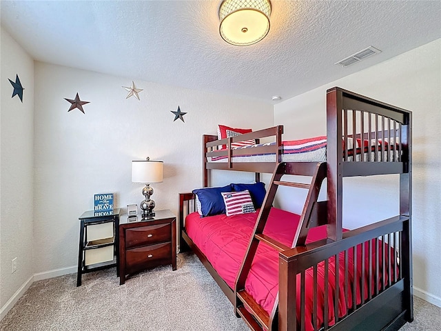 carpeted bedroom featuring visible vents, baseboards, and a textured ceiling