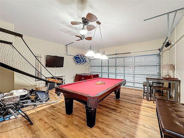 game room featuring light wood finished floors, concrete block wall, and ceiling fan