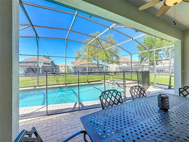 view of swimming pool with a patio area, ceiling fan, a residential view, and glass enclosure
