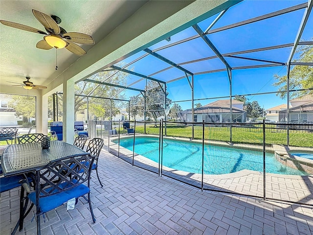 view of swimming pool featuring a patio area, a pool with connected hot tub, a ceiling fan, and glass enclosure