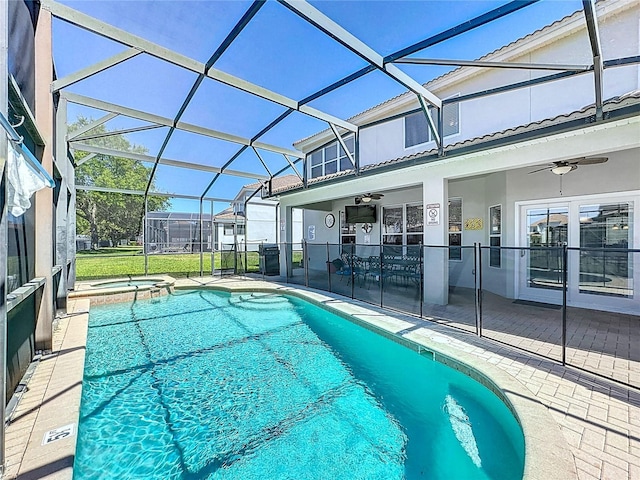 view of swimming pool with a pool with connected hot tub, ceiling fan, glass enclosure, and a patio
