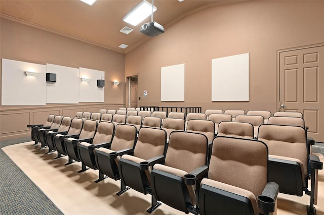 carpeted home theater featuring high vaulted ceiling, ornamental molding, visible vents, and a wainscoted wall