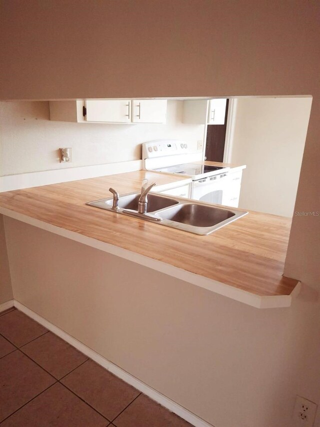 kitchen featuring tile patterned flooring, a sink, white range with electric cooktop, and white cabinets