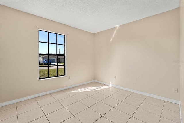 unfurnished room featuring baseboards, a textured ceiling, and light tile patterned floors