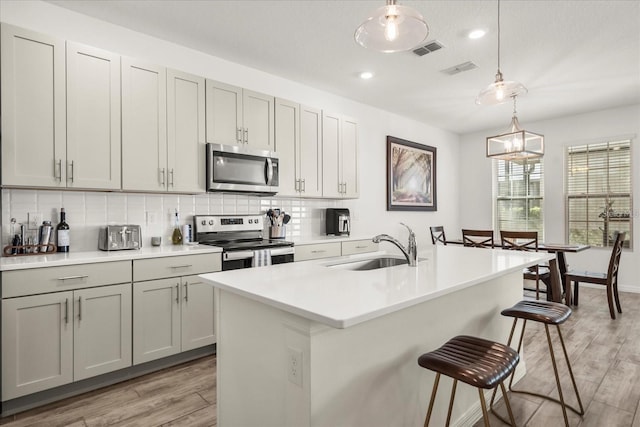 2710 Bolzano Dr, Apopka, FL 32712 - kitchen with tasteful backsplash, visible vents, a sink, stainless steel appliances, and light wood-style flooring