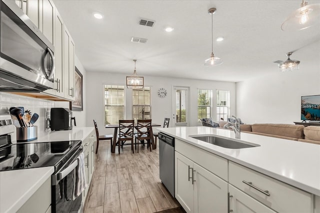 2710 Bolzano Dr, Apopka, FL 32712 - kitchen with visible vents, appliances with stainless steel finishes, light countertops, a sink, and backsplash