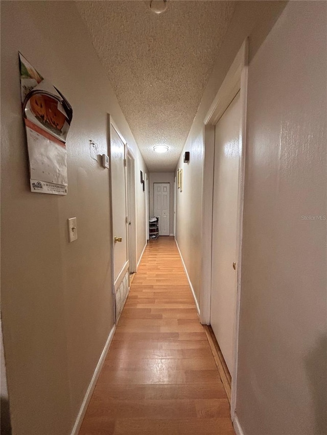 3219 Chariot Pl, Orlando, FL 32818 - hallway featuring baseboards, light wood finished floors, and a textured ceiling