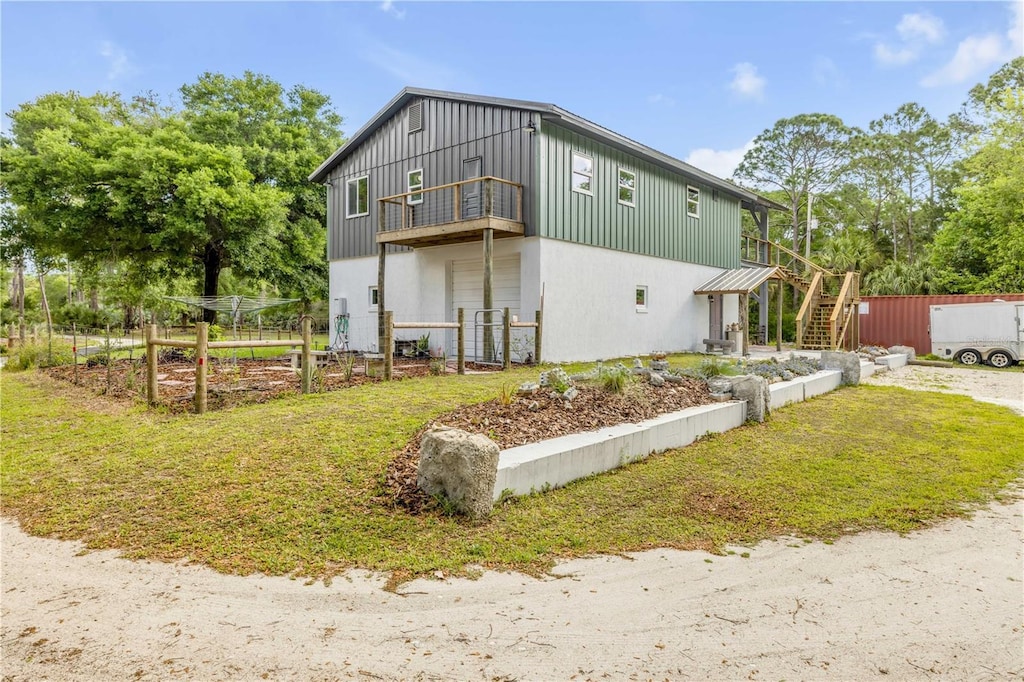 back of property featuring board and batten siding, stairway, and a garden