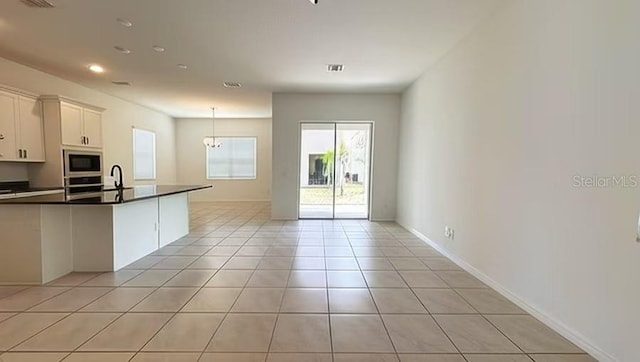 kitchen featuring baseboards, light tile patterned floors, open floor plan, dark countertops, and stainless steel appliances