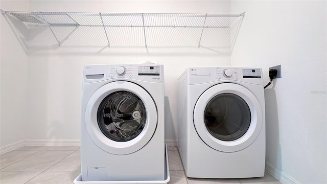 washroom featuring light tile patterned floors, baseboards, washer and dryer, and laundry area