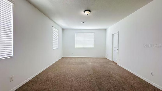 carpeted spare room with baseboards and visible vents