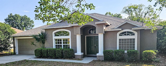 view of front of property with concrete driveway, stucco siding, roof with shingles, and a garage