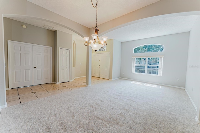 empty room with a notable chandelier, baseboards, arched walkways, and carpet floors