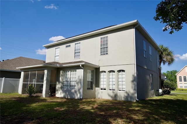 13520 Meadow Bay Loop, Orlando, FL 32824 - rear view of house featuring a sunroom, stucco siding, fence, and a lawn