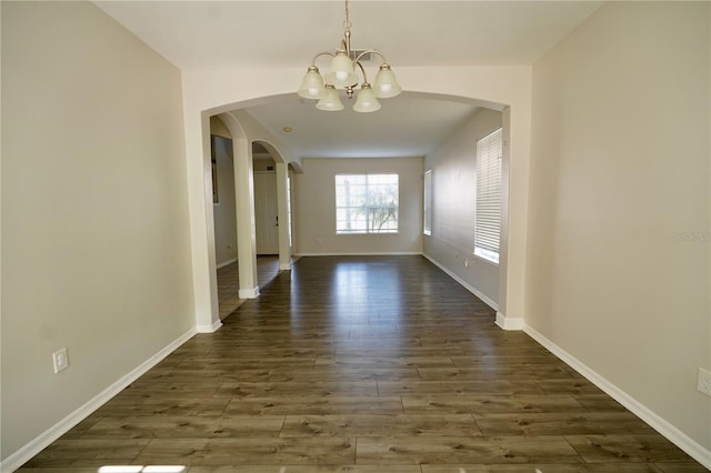 13520 Meadow Bay Loop, Orlando, FL 32824 - unfurnished dining area featuring baseboards, arched walkways, dark wood-type flooring, and an inviting chandelier