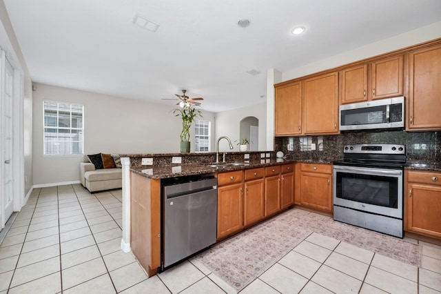 13520 Meadow Bay Loop, Orlando, FL 32824 - kitchen featuring appliances with stainless steel finishes, brown cabinets, ceiling fan, and backsplash