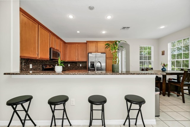 13520 Meadow Bay Loop, Orlando, FL 32824 - kitchen with stainless steel appliances, a breakfast bar area, a peninsula, decorative backsplash, and recessed lighting