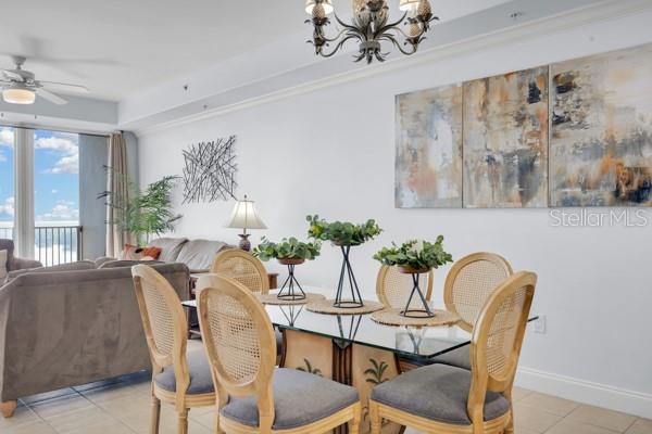 13427 Blue Heron Beach Dr Unit 1205, Orlando, FL 32821 - dining room with ceiling fan with notable chandelier, baseboards, and light tile patterned floors
