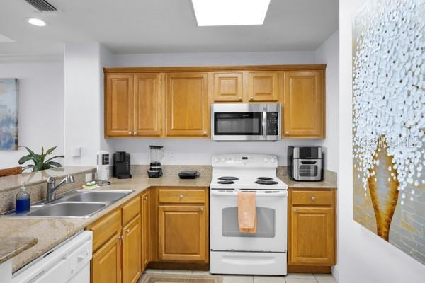 13427 Blue Heron Beach Dr Unit 1205, Orlando, FL 32821 - kitchen with light tile patterned flooring, visible vents, white appliances, recessed lighting, and a sink