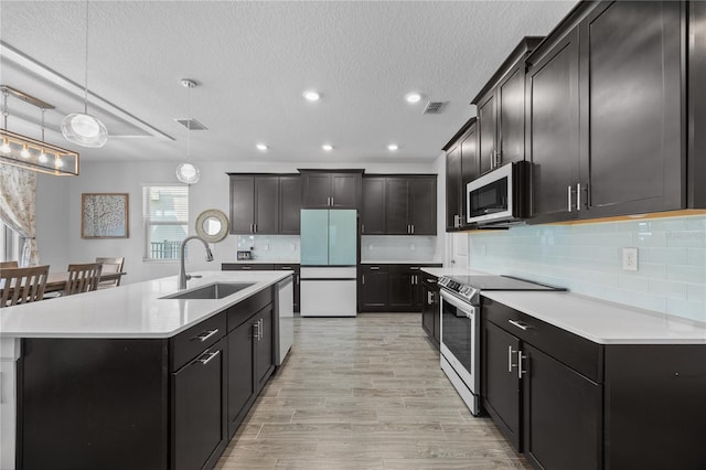 12048 Imaginary Way, Orlando, FL 32832 - kitchen with a sink, a kitchen island with sink, light countertops, appliances with stainless steel finishes, and visible vents