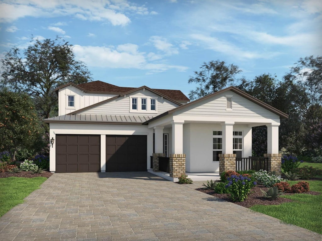 view of front of home with decorative driveway, a garage, a standing seam roof, metal roof, and covered porch