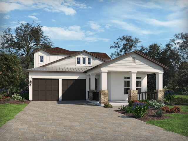 view of front of home with decorative driveway, a garage, a standing seam roof, metal roof, and covered porch