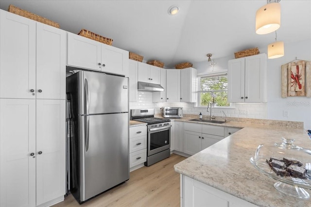 kitchen featuring vaulted ceiling, stainless steel appliances, under cabinet range hood, a sink, and white cabinets