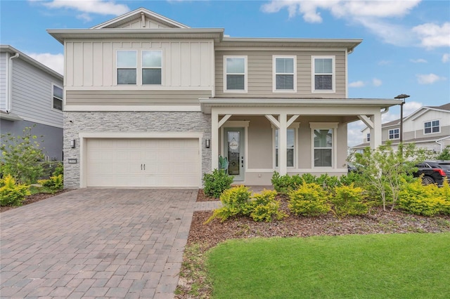 13640 Haulover Beach Ln, Orlando, FL 32827 - view of front of property with a porch, stone siding, a garage, board and batten siding, and decorative driveway