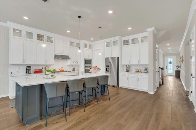 13640 Haulover Beach Ln, Orlando, FL 32827 - kitchen featuring under cabinet range hood, light countertops, a spacious island, and appliances with stainless steel finishes