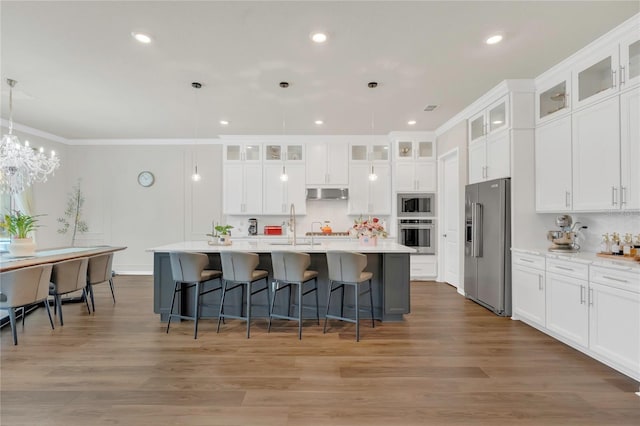 13640 Haulover Beach Ln, Orlando, FL 32827 - kitchen featuring white cabinets, light countertops, a kitchen bar, and stainless steel appliances