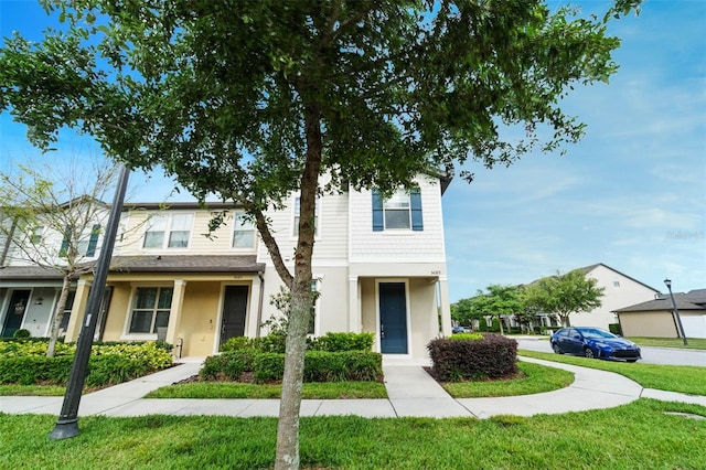 townhome / multi-family property featuring a front yard and stucco siding
