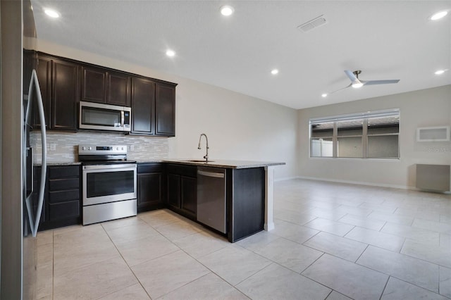 kitchen with visible vents, a peninsula, tasteful backsplash, appliances with stainless steel finishes, and a sink
