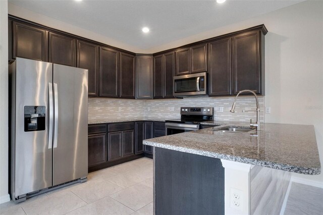 kitchen featuring stone counters, a sink, stainless steel appliances, and dark brown cabinets