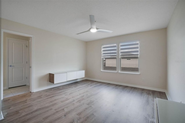 empty room featuring baseboards, wood finished floors, and ceiling fan