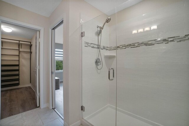 full bathroom featuring a stall shower, baseboards, and a walk in closet