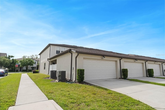 view of home's exterior with stucco siding, central AC, concrete driveway, and a yard
