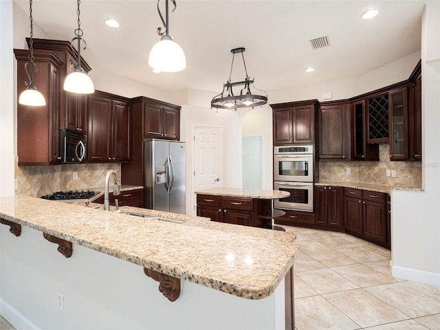 kitchen featuring a breakfast bar area, a sink, a peninsula, and appliances with stainless steel finishes
