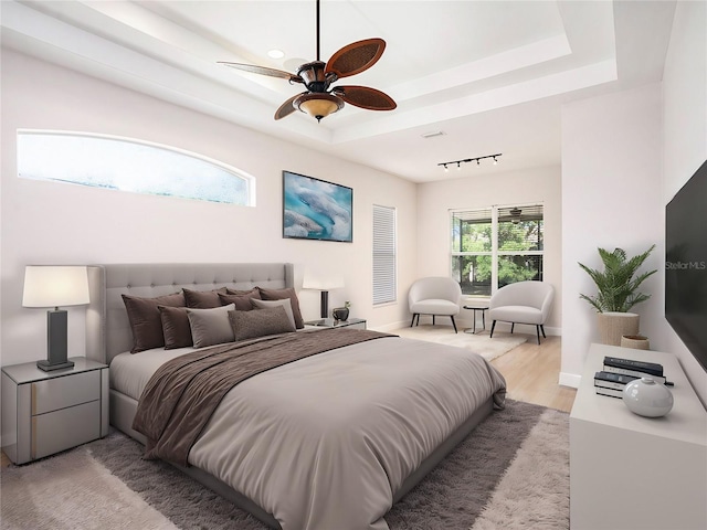 bedroom with track lighting, light wood-style floors, a ceiling fan, and a raised ceiling