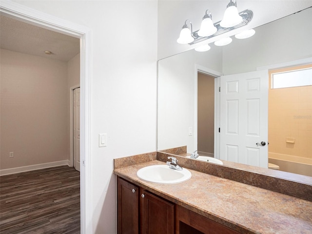 full bathroom with baseboards, wood finished floors, vanity, and an inviting chandelier