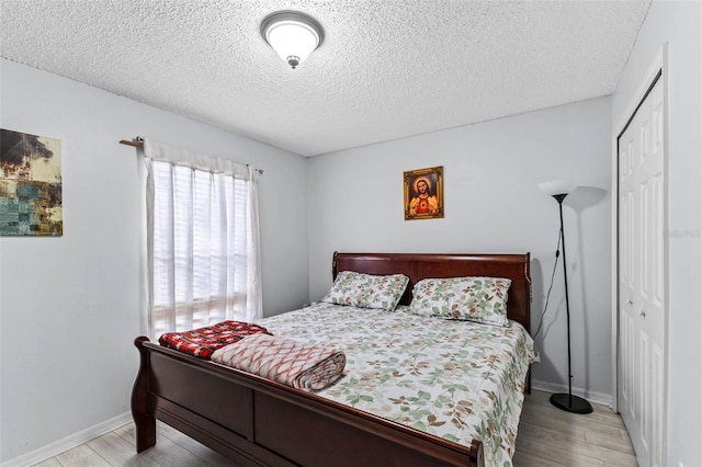 bedroom featuring wood finished floors, a closet, and baseboards