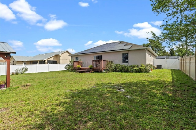 exterior space with central air condition unit, a fenced backyard, a wooden deck, and a gate