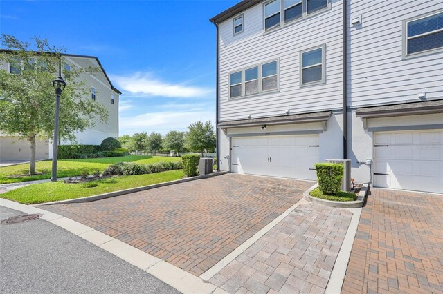 7772 Sweet Star Ave, Orlando, FL 32836 - view of property exterior featuring an attached garage, decorative driveway, and central air condition unit