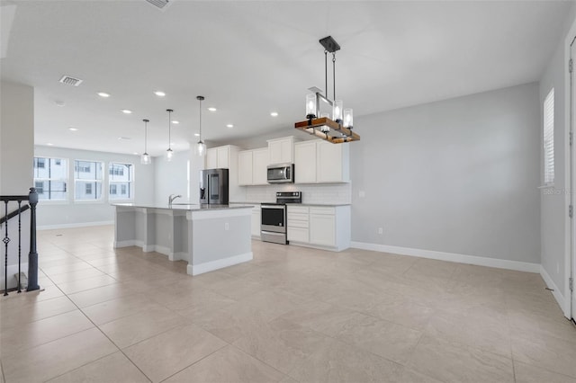 7772 Sweet Star Ave, Orlando, FL 32836 - kitchen featuring tasteful backsplash, light countertops, appliances with stainless steel finishes, an island with sink, and white cabinetry