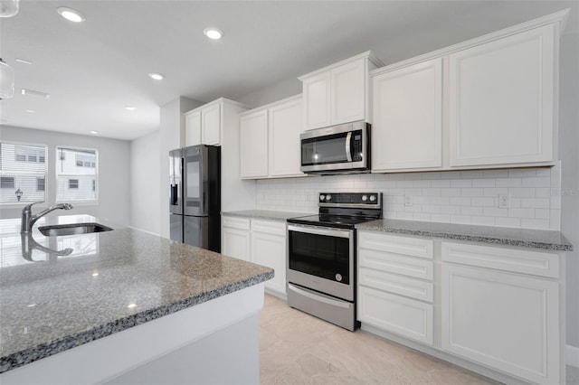 7772 Sweet Star Ave, Orlando, FL 32836 - kitchen with dark stone counters, a sink, white cabinets, and stainless steel appliances