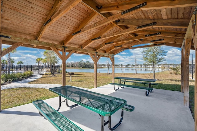 view of community featuring a water view, fence, a yard, and a patio