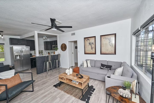 1405 Smith Dr N, Titusville, FL 32780 - living area featuring light wood finished floors, a wealth of natural light, visible vents, and ceiling fan