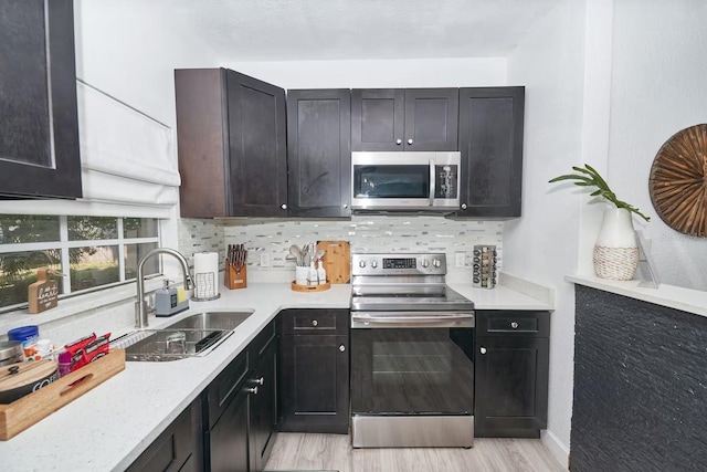 1405 Smith Dr N, Titusville, FL 32780 - kitchen with light countertops, a sink, stainless steel appliances, light wood-style floors, and decorative backsplash
