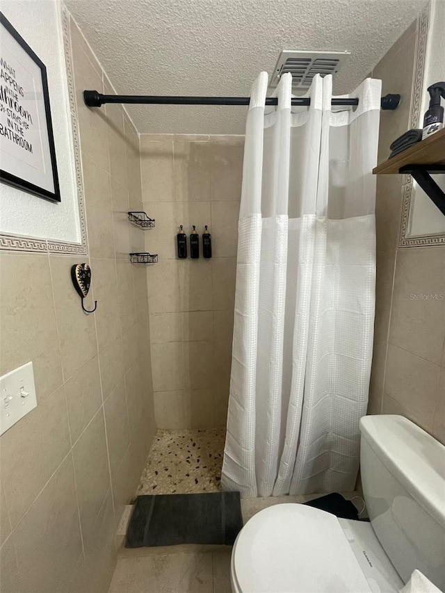 1405 Smith Dr N, Titusville, FL 32780 - full bathroom with toilet, tiled shower, tile walls, and a textured ceiling